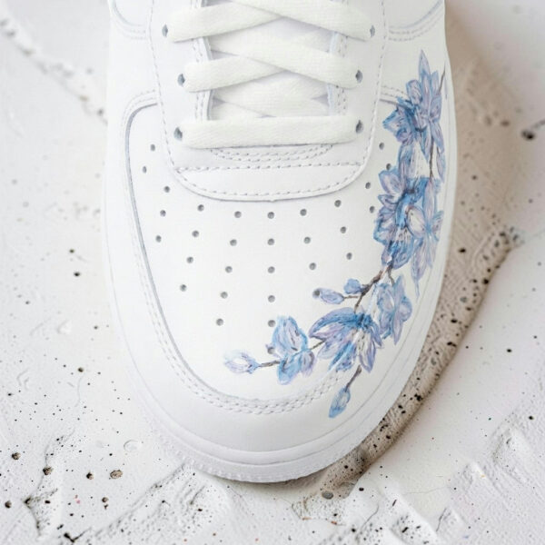 White Air Force 1 sneaker with hand-painted blue cherry blossom design.