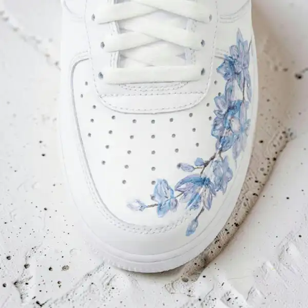 White Air Force 1 sneaker with hand-painted blue cherry blossom design.