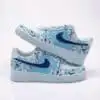 Custom hand-painted blue splash Nike Air Force 1 shoes for sneaker enthusiasts. Unique, artistic des.