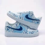 Custom hand-painted blue splash Nike Air Force 1 shoes for sneaker enthusiasts. Unique, artistic des.