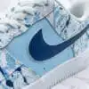 Hand-painted blue splash design on Air Force 1 sneaker with Nike swoosh.