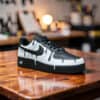 Custom white drip Air Force 1 sneakers with black accents on a wooden surface.