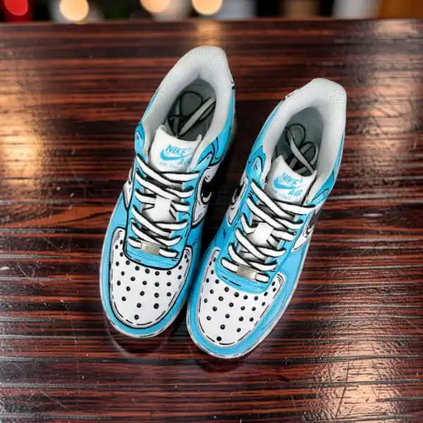 Hand-painted blue cartoon drip Nike AF1 sneakers on wooden surface.