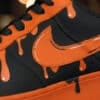 Hand-painted orange drip design on black Nike Air Force 1 sneakers. Unique custom sneaker art for st.