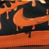 Custom orange drip Nike Air Force 1 sneakers with black accents and unique paint design.